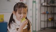 Free stock video - Little girl eating an apple in classroom in a montessori school