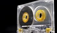 Rotating yellow transparent audio cassette on a black background. Close up. Scene C.