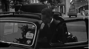 1957: News: Kenneth Kendall Sticking Lift Label on Car