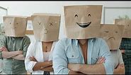 Portrait of businesspeople wearing paper bags with emoji on heads standing with arms crossed in