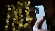 Premium stock video - Taking photos with smartphone camera flash - person using cell phone with triple lens camera and depth sensor to take photos in the dark with an led flash