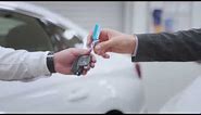 Car Dealer Handing Over New Car Key To Customer at Showroom