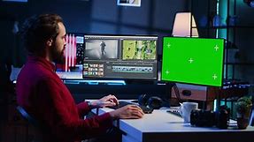 Video editor analyzing film montage on green screen monitor before editing color grading and lighting in creative office. Post production studio employee working with raw footage on mockup PC