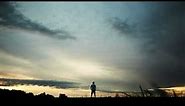 Man Standing In Field Under Cloudy Sunrise Sunset Sky 4K Christian Worship Background Motion Loop
