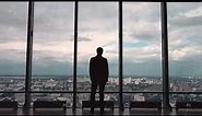 Rear view of businessman in an office with panoramic city view. Businessman admires the city from