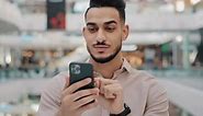 Happy Smiling Young Arab Male Holding Phone Amazed Joyful Guy Get Cash Prize Lottery Winner Hispanic