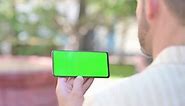 Middle Aged Man Holding Phone with Green Screen Outdoor