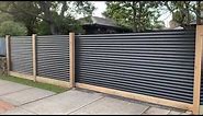 Corrugated steel exposed post fence with sleeper. Automatic sliding gate.