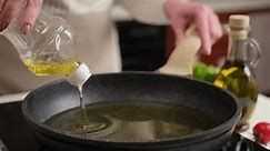 A woman pours vegetable oil into a frying pan on the induction stove