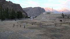 People are playing cricket and soccer on a field in Skardu, Pakistan
