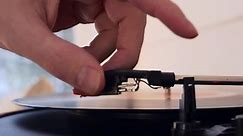 Close-up of a man starting a record player and a vinyl record starts spinning, a man lowers the needle to play music. Record player for listening to classical music. Vintage gramophone with record.