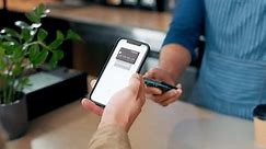 Customer, pos machine and phone for payment, coffee or tap transaction in checkout at cafe. Closeup of person, hands and paying with smartphone for cappuccino, tea or beverage at cafeteria restaurant