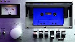 Blue Audio Cassette Tape Rolling in Vintage 1980s Deck Player With VU Meters, Close Up