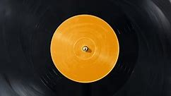 Black vinyl Retro record on DJ turntable. Black vinyl background with yellow screen in center. Rotating plate close up. Party. Loop. Macro View from above Popular Disco Trends 60s, 70s, 80s, 90s