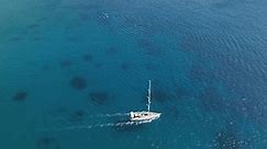A sailing yacht moving through the water off the coast of Ios Island in Greece.