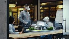 Male designer uses VR headset and wireless controllers, presents smart home exterior design project in virtual reality to coworkers. Modern hi-tech company. 3D hologram. Future digital technologies.