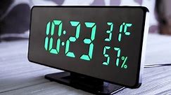 Digital Clock Showing Time on Green Display 10:23 AM, Temperature, Air Humidity. Modern mirror clock, alarm clock with a thermometer, hydrometer standing on a desk on white background. Time concept.