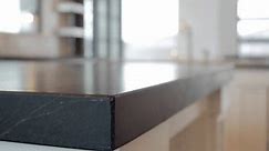 Pan close-up of black soapstone kitchen countertop in modern home.