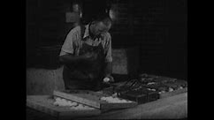 1950s: Hatchery worker places eggs in pedigree baskets and writes on records forms. Hand holds egg with numbers on shell.