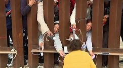 Migrants charge phones through gaps of 30ft fence on US border