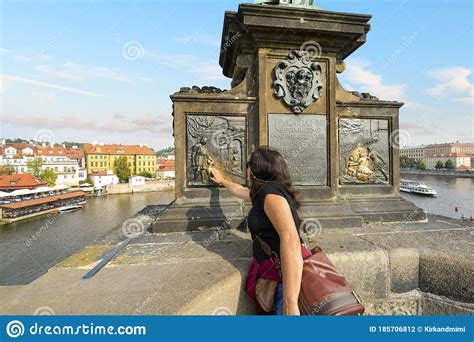 A Tourist Rubs The Bronze Plaque On The Statue Of Saint