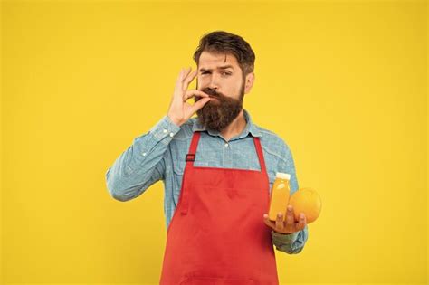 Premium Photo Man In Apron Licking Finger Holding Orange And Juice
