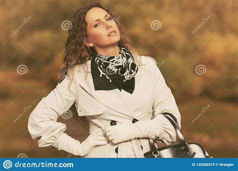 beautiful fashion woman in white trench coat walking outdoor stock