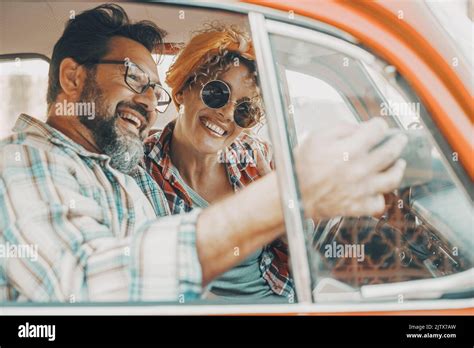 happy couple having fun inside a car during travel adventure cheerful