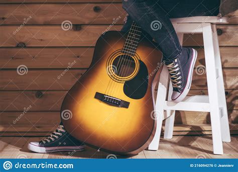 Acoustic Six String Yellow Brown Guitar And Legs Of Female Sitting On