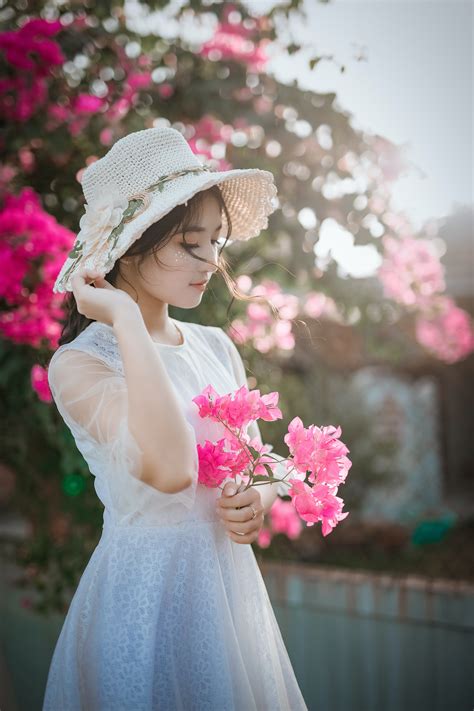 woman wearing sun hat and white dress holding pink