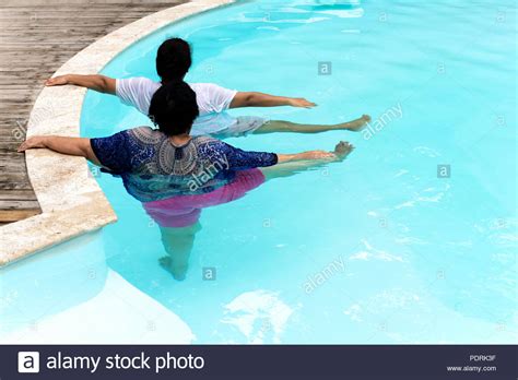 Two Senior Women Doing Aqua Gym Exercise In Outdoor Swimming Pool Stock