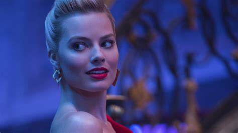 Margot Robbie Is Wearing Red Dress With A Blur Background Facing One
