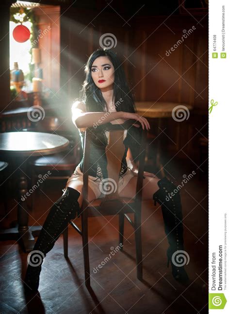beautiful girl with long leather boots sitting on chair in