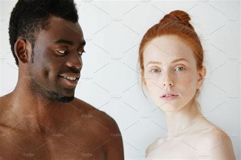 portrait of happy loving interracial couple shirtless african man looking at his nude redhead
