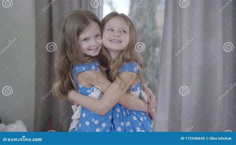 portrait of two happy caucasian twin sisters hugging indoors pretty