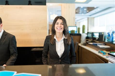 Female Receptionist Standing At Hotel Front Desk Stock