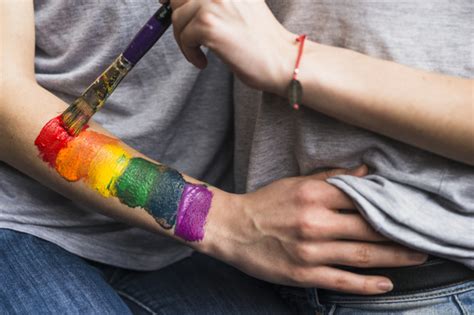 mano de mujer pintando la bandera del arco iris sobre la mano de la