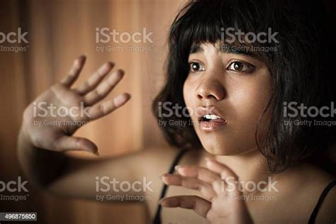 frightened teenage girl looking away and hiding herself behind hands
