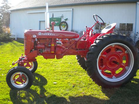 red farmall tractor parked  front   building  grass   door open