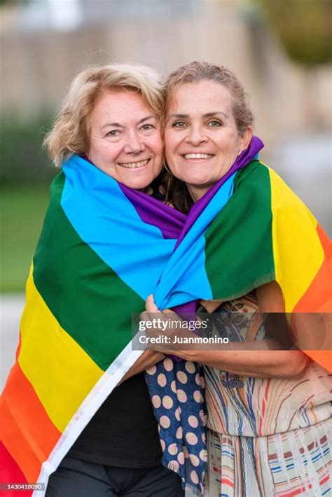 Smiling Happy Mature Lesbian Couple Posing Wrapped In A Rainbow Flag
