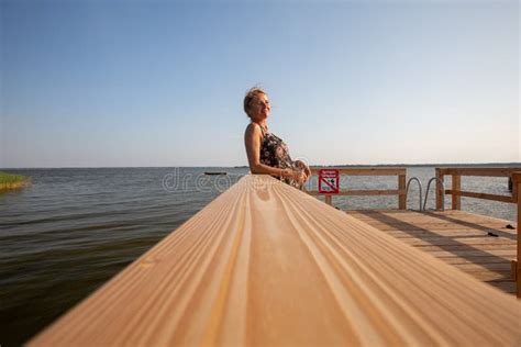 View Of A Relaxing Mature Woman Sitting Of A Pier Stock Image Image