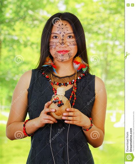 vrouw uit de amazone met gezichtsverf en het zwarte kleding stellen voor camera die houten fles