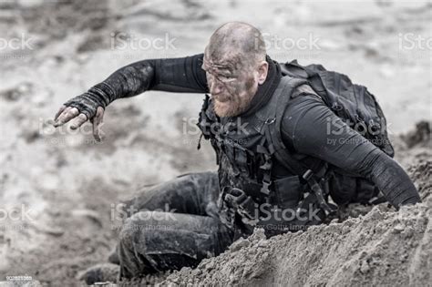 redhead shaved male military member training hard on a sand hill run