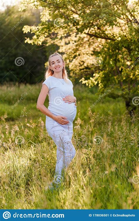 a smiling thirty year old pregnant woman in a gray t shirt