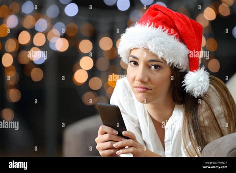 frustrated woman holding a phone on christmas lying on a couch in the