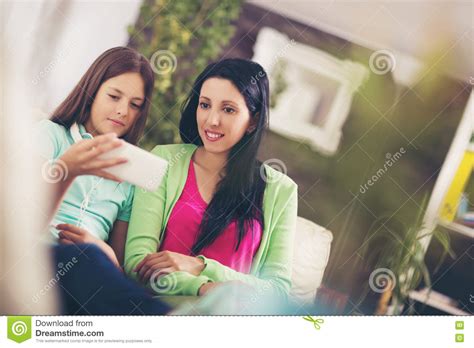 happy mother and her cute teen daughter are looking at mobile phone stock image image of