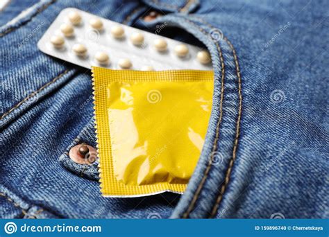 yellow condom and birth control pills in pocket of jeans safe sex