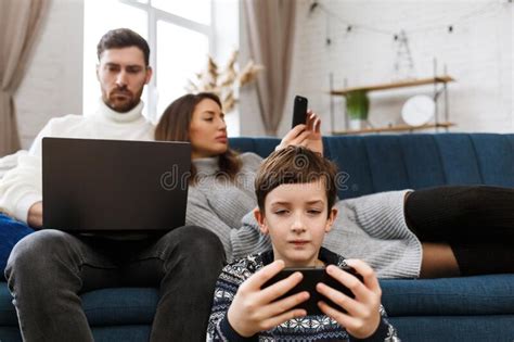 Mother Father And Son Using Laptop And Mobile Phones At