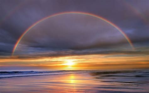 a double rainbow over the sun setting below the ocean s