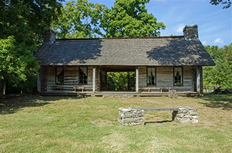 log cabin sits   middle   grassy area  picnic tables  benches